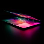 A glowing laptop with colorful lighting on a dark background